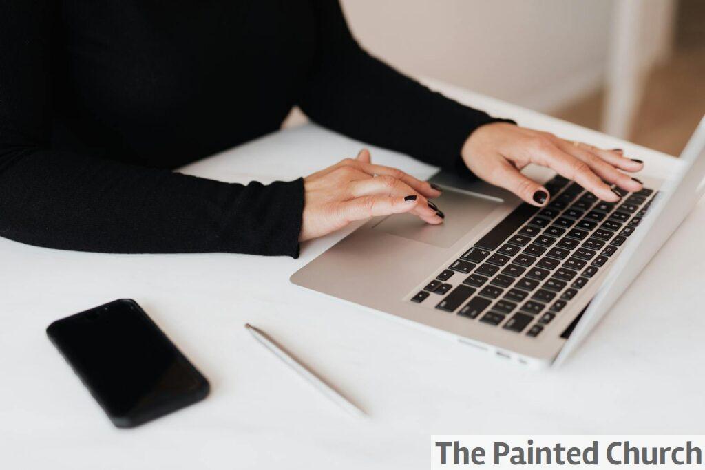 Crop faceless woman working on netbook in office