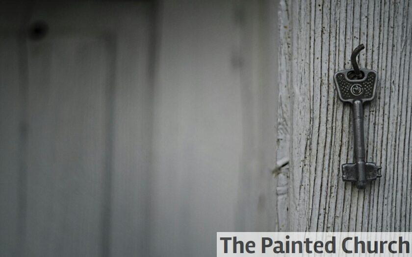 A vintage iron key hangs on a textured weathered wooden wall, evoking nostalgia and mystery.