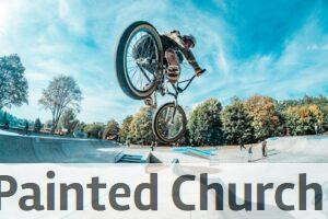 Rider performs a stunning BMX jump at an outdoor skatepark on a clear day.