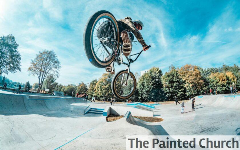 Rider performs a stunning BMX jump at an outdoor skatepark on a clear day.