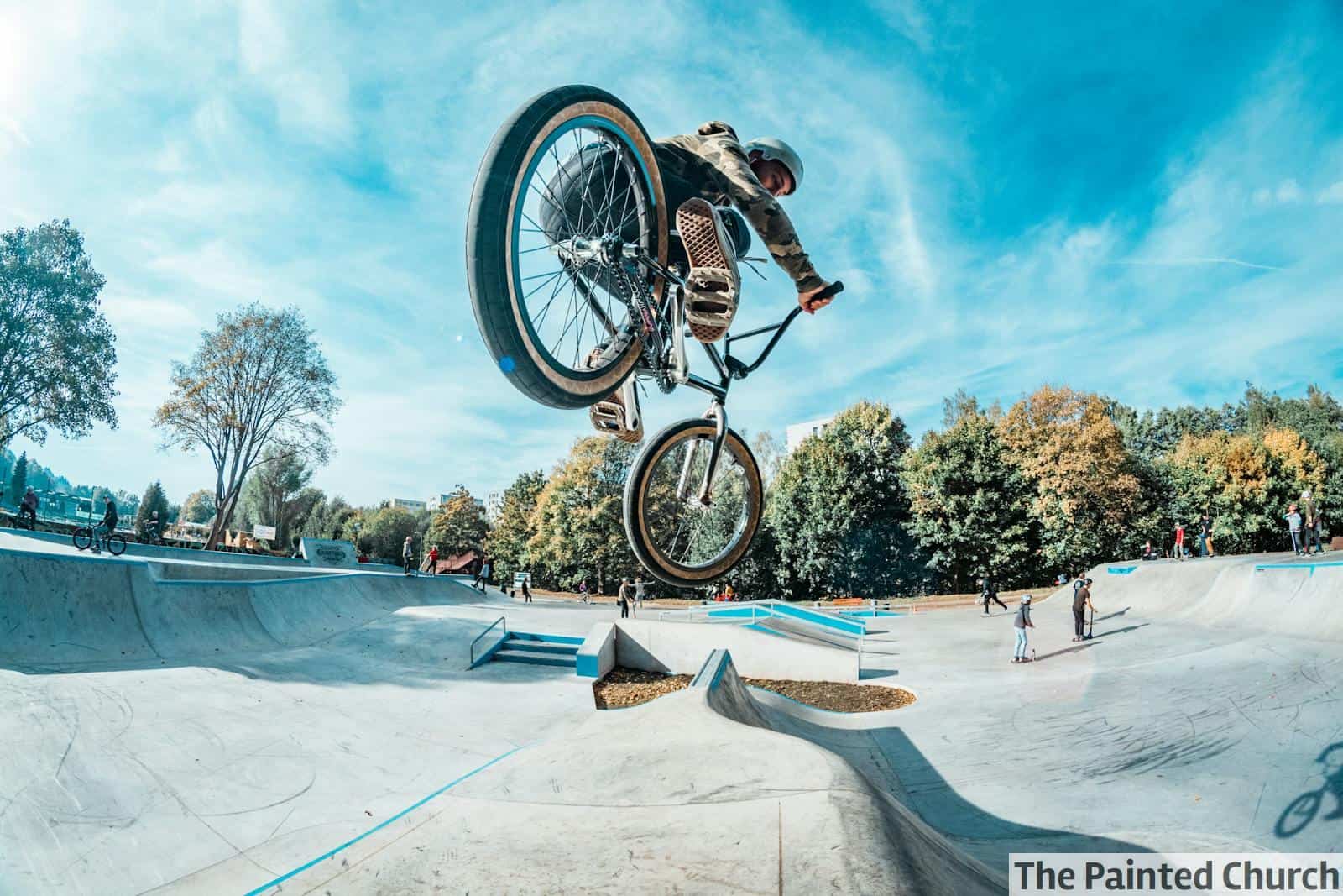 Rider performs a stunning BMX jump at an outdoor skatepark on a clear day.
