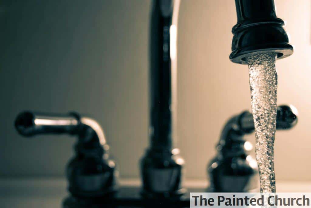 A detailed shot of water flowing from a steel faucet, ideal for themes on cleanliness or plumbing.
