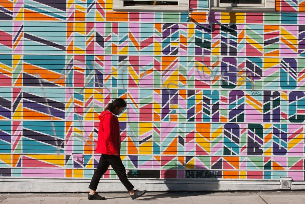 Persona caminando junto a una pared con un mural geométrico de colores